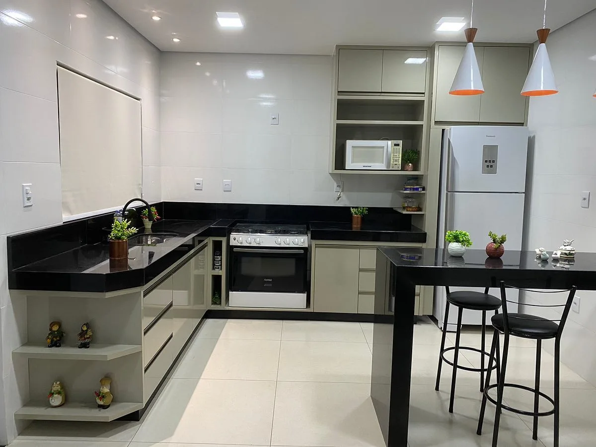 Cozinha planejada em L com bancada preta, balcão com banquetas e nichos laterais